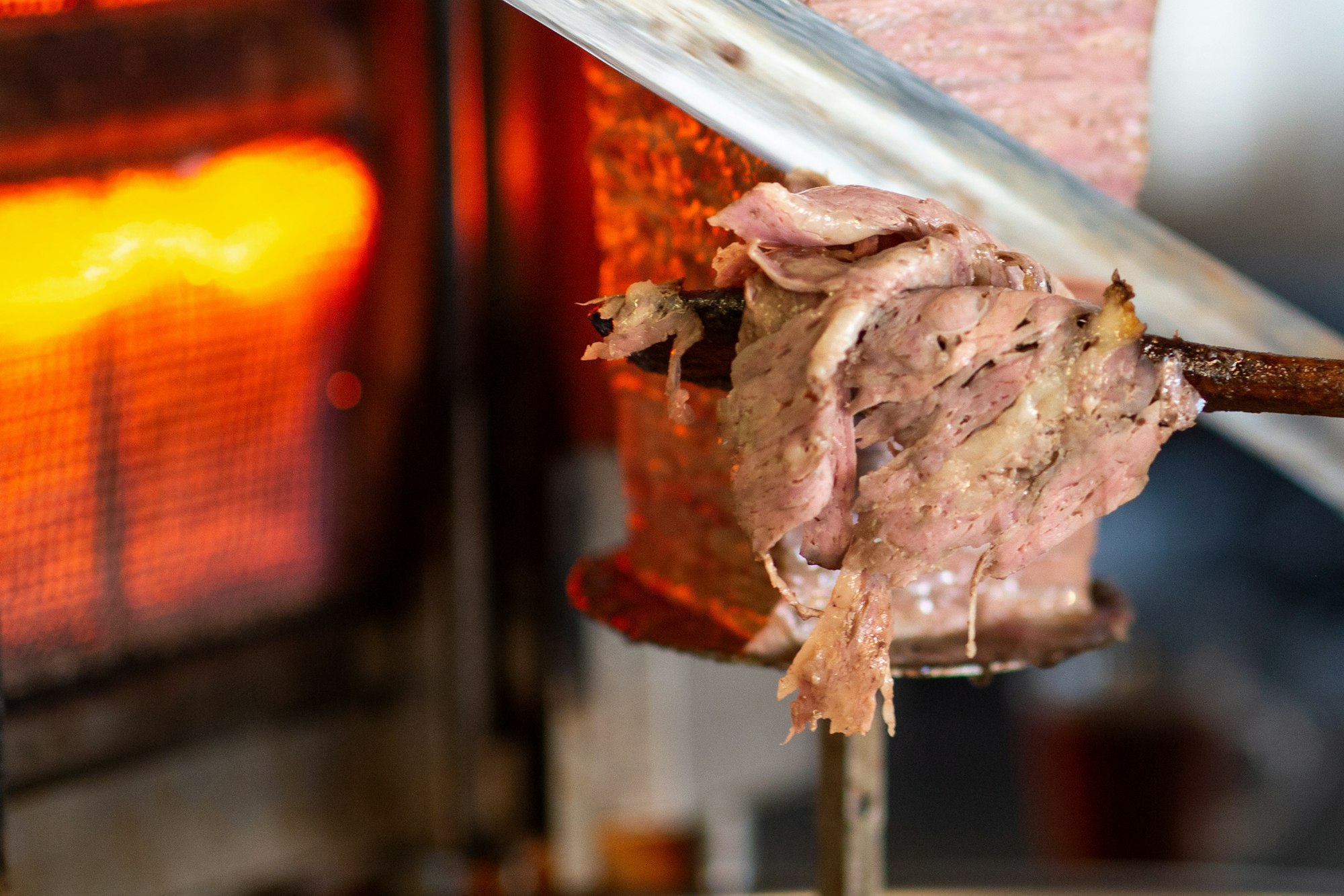 Closeup detail view of Turkish Doner, chef is slicing the doner